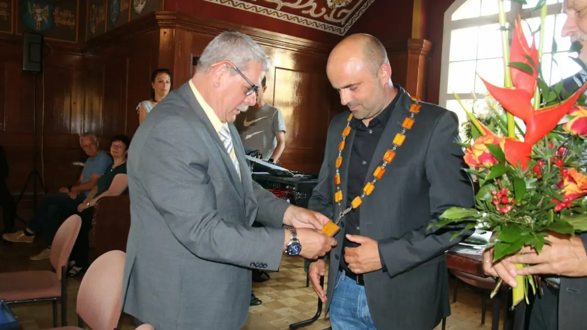 Die Amtskette aus Bernstein und Silber legt Paul Bruse, stellvertretender Vorsitzender der Stadtverordnetenversammlung dem neuen Bürgermeister Jens Richter um den Hals.
Die Amtskette aus Bernstein und Silber legt Pau Bruse den neuen Bürgermeister Jens Richter um den Hals.