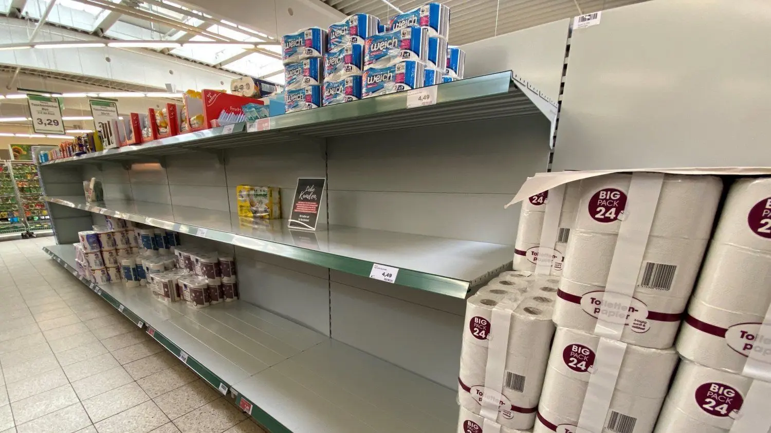 Wie hier in einem Cottbuser Einkaufsmarkt klaffen inzwischen vielerorts Lücken in den Regalen. Aus Angst vor einer möglichen Quarantäne decken sich die Menschen vor allem mit Toilettenpapier, Konserven, Nudeln und Tütensuppen ein. Mit einem Schild im Regal wird um Verständnis für den Engpass aufgrund erhöhter Nachfrage geworben.