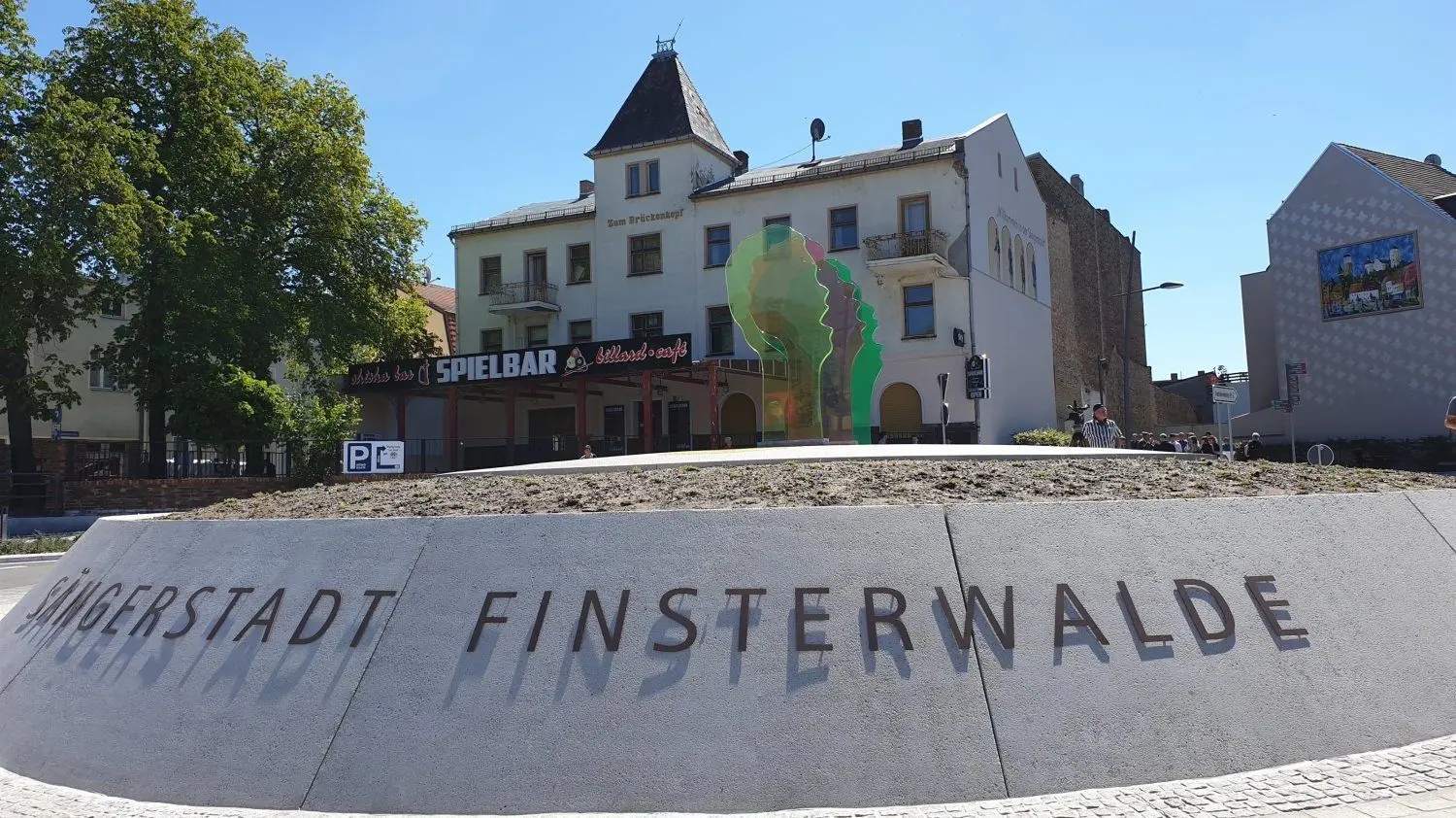 Ein Schriftzug erinnert Besucher der Stadt Finsterwalde – neben den bunten Sängerköpfen – daran, wo sie gelandet sind.