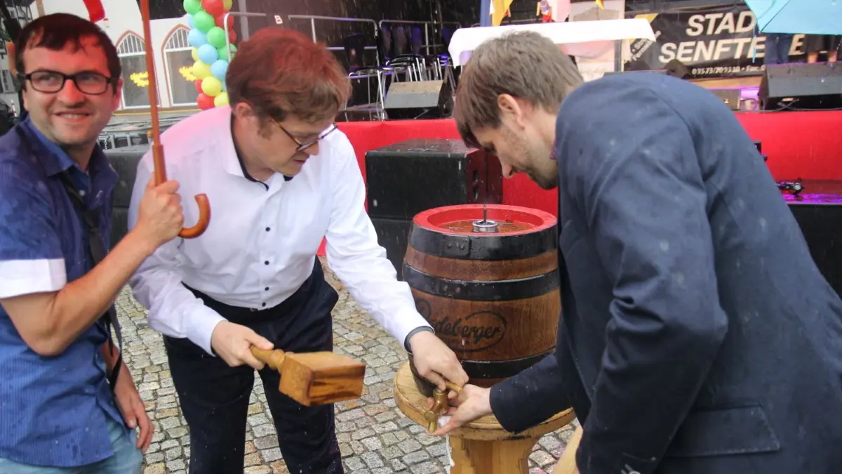 Im strömenden Regen wurde in diesem Jahr der traditionelle Bierfassanstich zur Eröffnung des Senftenberger Peter-und-Paul-Marktes vorgenommen.
Diesmal zu zweit, international und unter dem Regenschirm wurde der traditionelle Bierfassanstich zur Eröffnung des Stadtfestes vorgenommen.