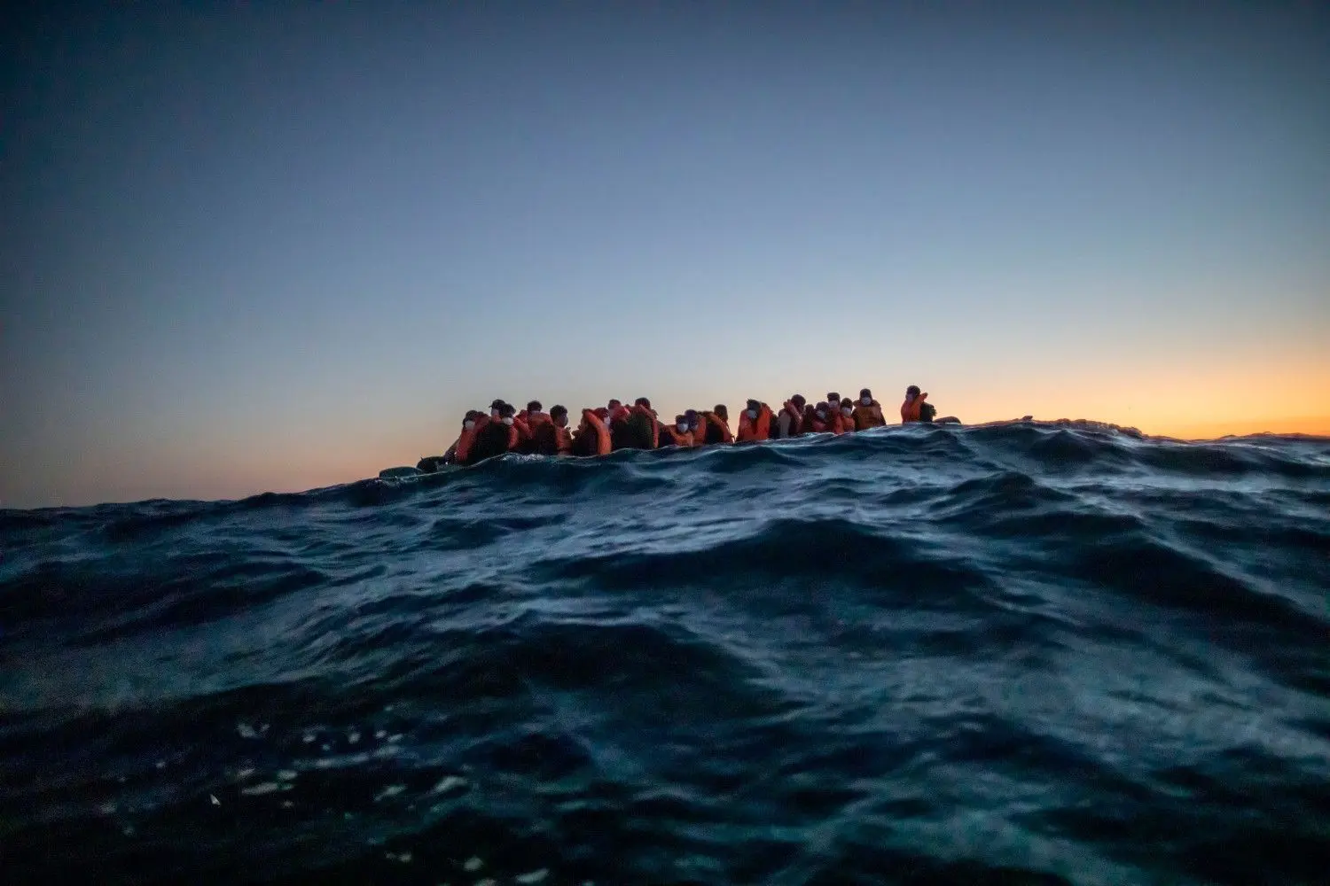 Migranten aus verschiedenen afrikanischen Nationen warten in einem Boot auf Helfer der spanischen NGO Open Arms, die sich ihnen 122 Meilen vor der libyschen Küste im Mittelmeer nähern. Foto: Bruno Thevenin/dpa