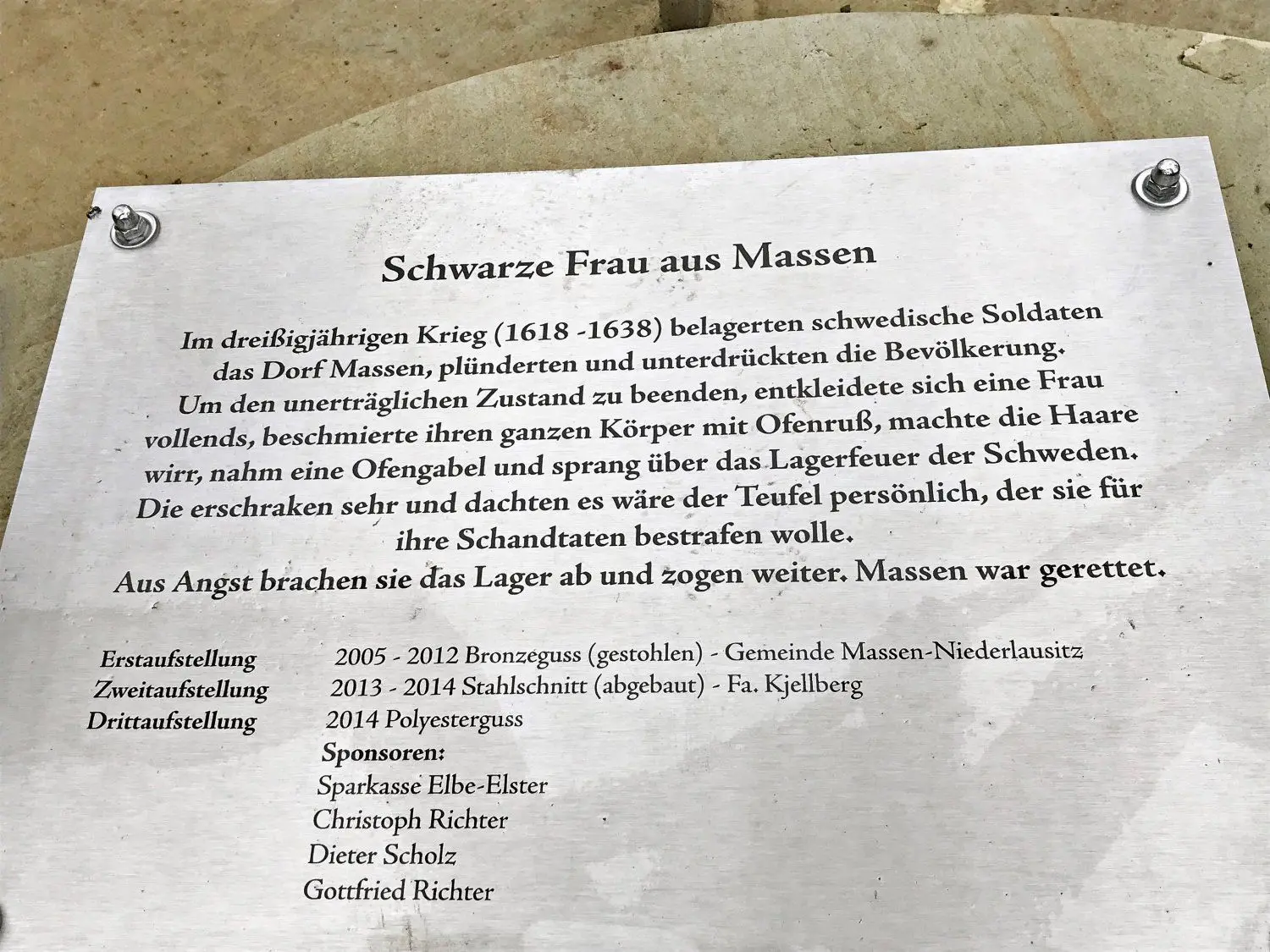Die Schwarze Frau auf dem Dorfanger in Massen ist erneut beschädigt worden. Unbekannte haben ihr einen Gabelzinken abgetrennt. Eine Tafel listet auf, wie oft sie schon erneuert werden musste.