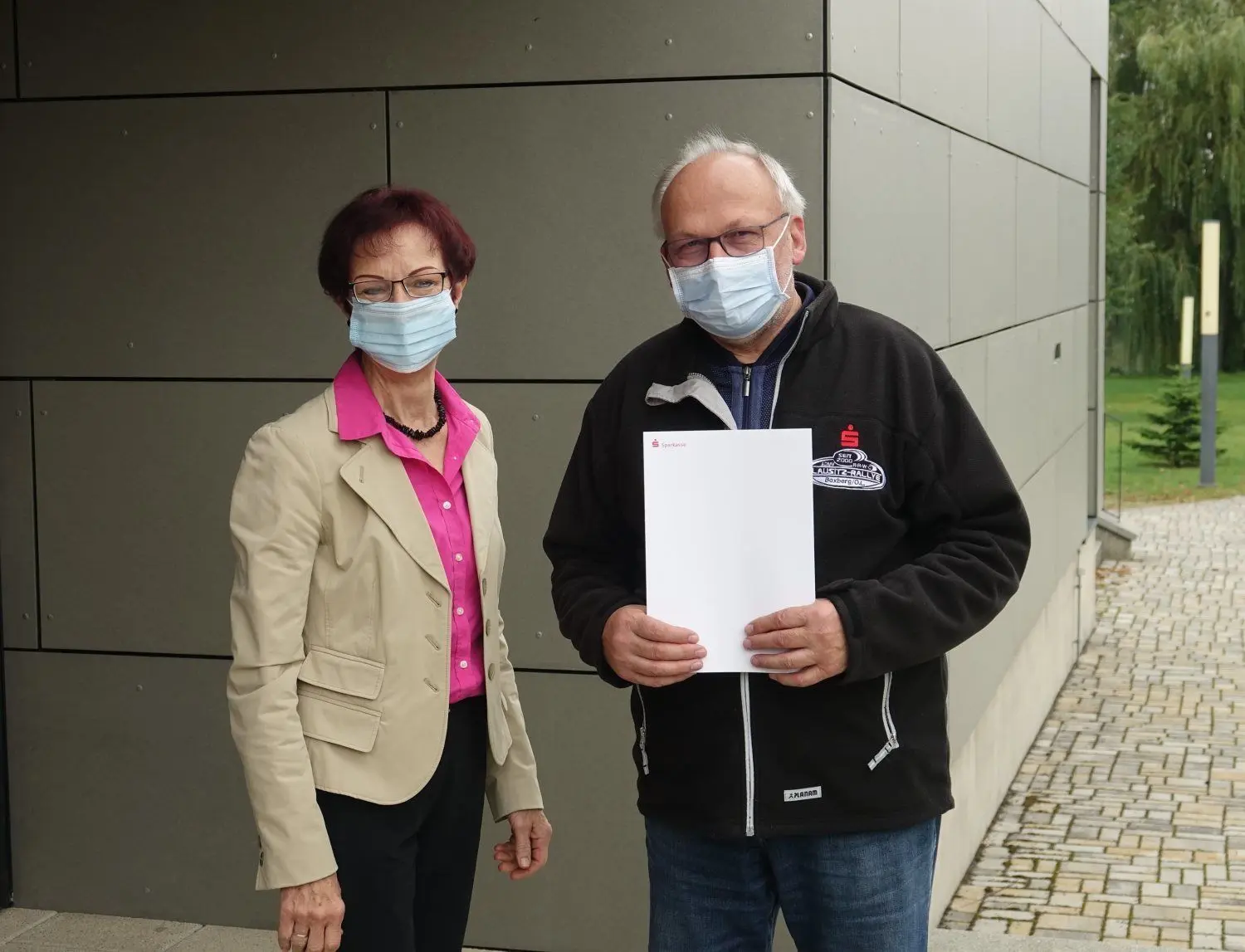 Ein Foto mit Symbolcharakter: Förderbescheid-Übergabe mit Maske durch Regina Risy von der Stiftung Sparkasse Oberlausitz-Niederschlesien an Wolfgang Rasper. Der Mund-Nasen-Schutz ist bei der Rallye 2020 an vielen Stellen Pflicht.