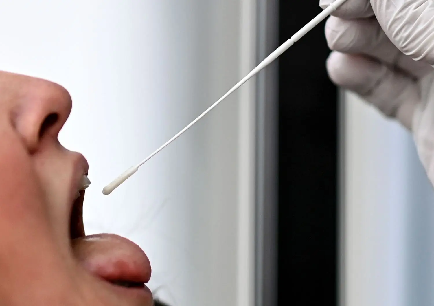 Bei einer jungen Frau wird ein Rachenabstrich für einen SARS-CoV-2-Antigentest, im Corona-Antigen-Schnelltest durchgeführt. Auch Beschäftigte in den Kinder und Jugendeinrichtungen sollen sich jetzt regelmäßig testen können.