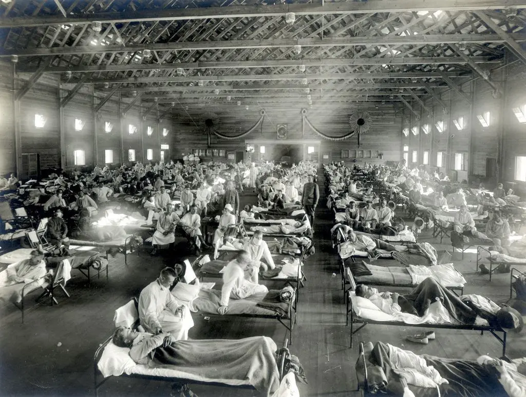 Patienten, die an der Spanischen Grippe erkrankt sind, liegen in Betten eines Notfallkrankenhauses im Camp Funston der Militärbasis Fort Riley in Kansas (USA) (Aufnahme von 1918). Die Spanische Grippe entwickelte sich in drei Wellen bis 1920 zur schlimmsten Grippe-Pandemie der Geschichte. In Deutschland starben etwa 300 000 Menschen daran, weltweit 25 bis 40 Millionen.