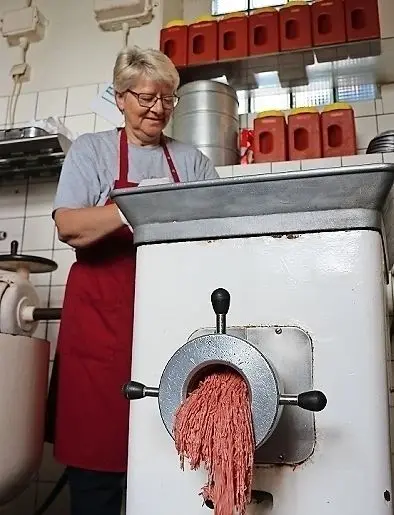 Jutta Pentke dreht die Fleischstücken durch den Fleischwolf.