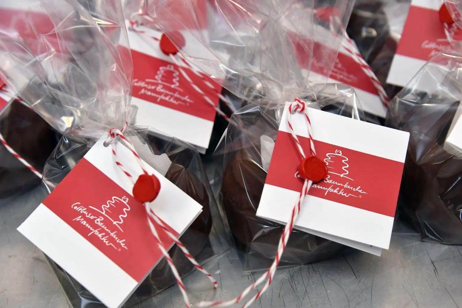 Die Minis gut verpackt in der Tüte  mit dem Logo der Cottbuser Baumkuchen Manufaktur als Anhänger, der auf das anschließend verplombte Schleifenband gefädelt wurde.