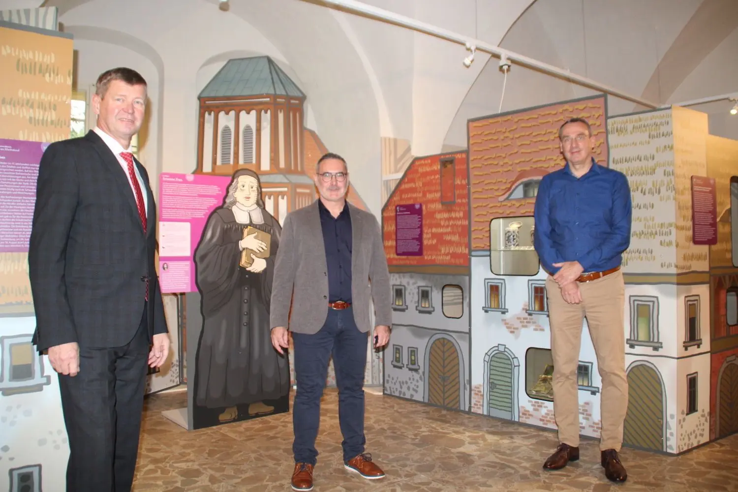 Vor der Kulisse des Ackerbürgerstädtchens Senftenberg im Jahr 1631 freuen sich Landrat Sigurd Heinze (l.) und Bürgermeister Andreas Fredrich (r.) zusammen mit Museumsdirektor Stefan Heinz über die Eröffnung des neuen Museums-Herzstückes.