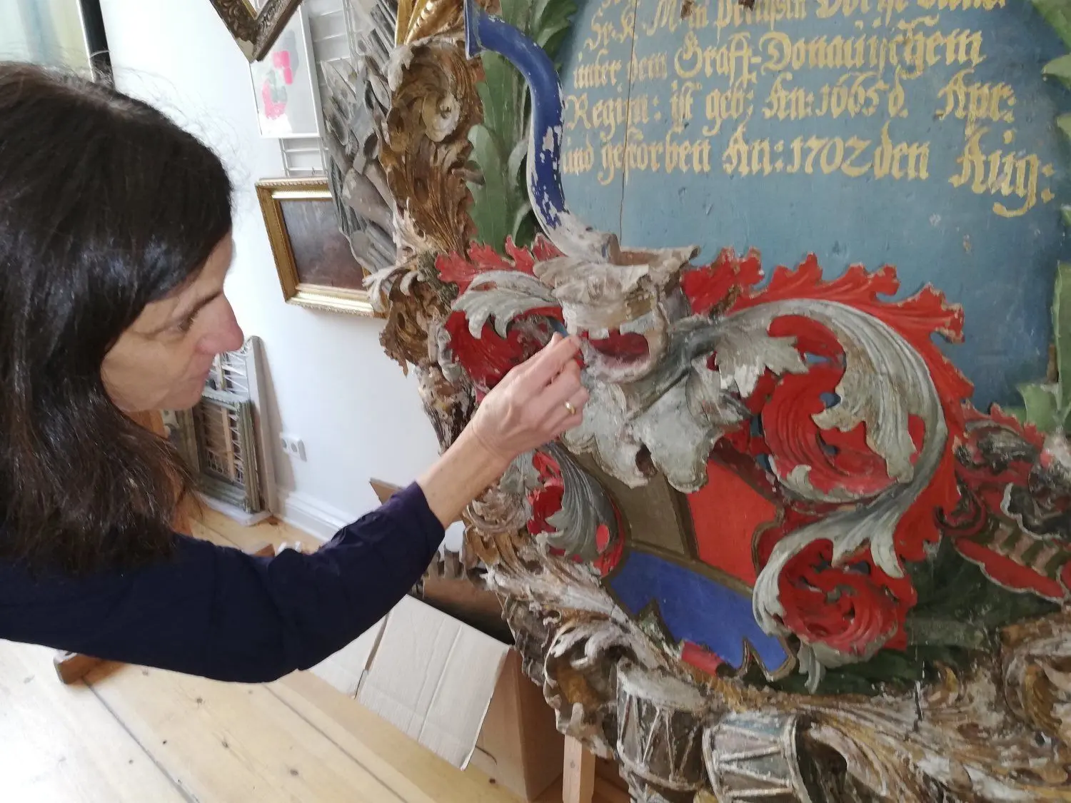 Restauratorin Christiane von Pannwitz am Familienwappen auf dem Epitaph für Adam Ernst von Pannwitz. Oben rechts ist der Schriftzug mit dem  falschen Sterbejahr zu sehen:  „gestorben An: 1702 den ..  Aug:“