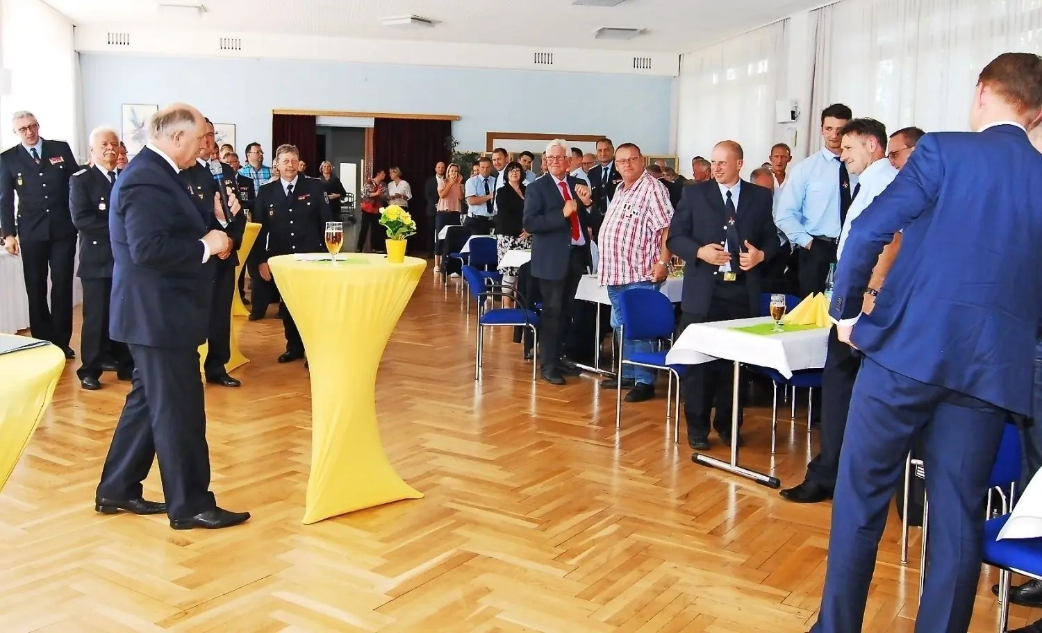 Hartmut Bastisch (links mit Mikrofon) bedankte sich bei den Anwesenden für die gute Zusammenarbeit, woraufhin sich die Gäste aus Respekt von den Plätzen erhoben. ⇥