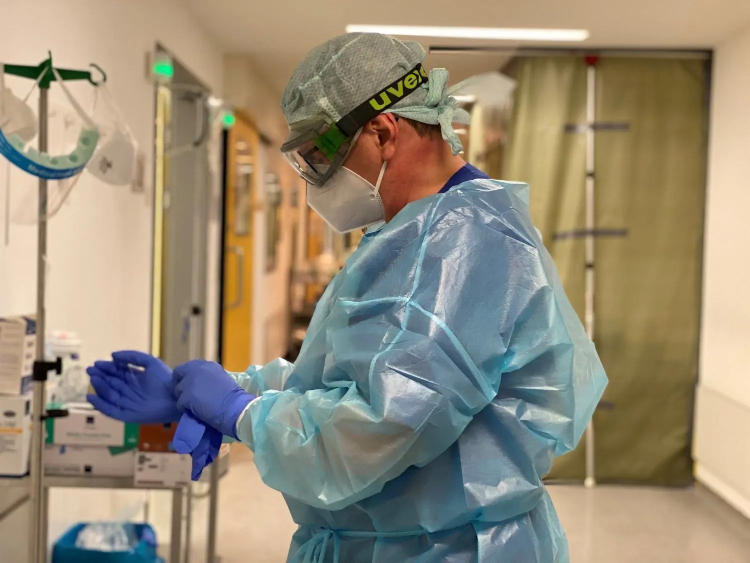 Ein Mitarbeiter des Carl-Thiem-Klinikums legt Schutzkleidung an und streift sich die Handschuhe über, bevor er zu den Covid-19-Patienten geht.