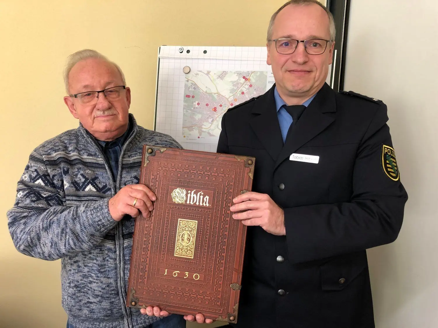 Selbst vor der Heiligen Schrift schreckte der Dieb nicht zurück. Die aus der Kreuzkirche geklaute Replika wurde in der Wohnung des Täters beschlagnahmt. Hoyerswerdas Revierleiter Tobias Hilbert übergab die Bibel an Seelsorger Hans-Joachim Grothe, der die Schrift wieder sicher  in die Vitrine der Kirche legt. Foto: Hummel