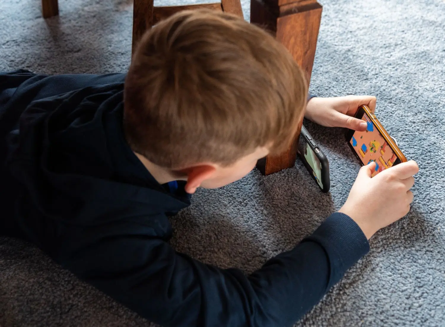 Ein Junge spielt ein Videospiel auf seinem Smartphone und überträgt es mit einem zweiten Handy per Facetime zu seinem Freund. Die Pandemie hat das Sozialverhalten von Kindern und Jugendlichen verändert.