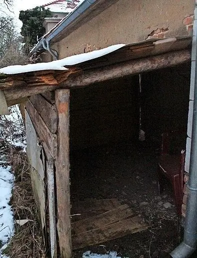 Ein kleiner Verschlag auf der Rückseite, im Hintergrund das Efeubewachsene Haupthaus, lässt größeren Sanierungsbedarf erahnen.