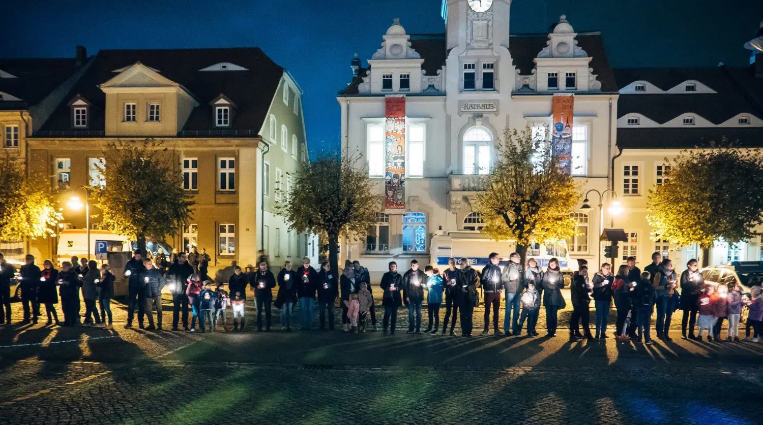 Besucher Ostritzer Friedensfestes bilden mit Kerzen in den Händen eine Menschenkette.