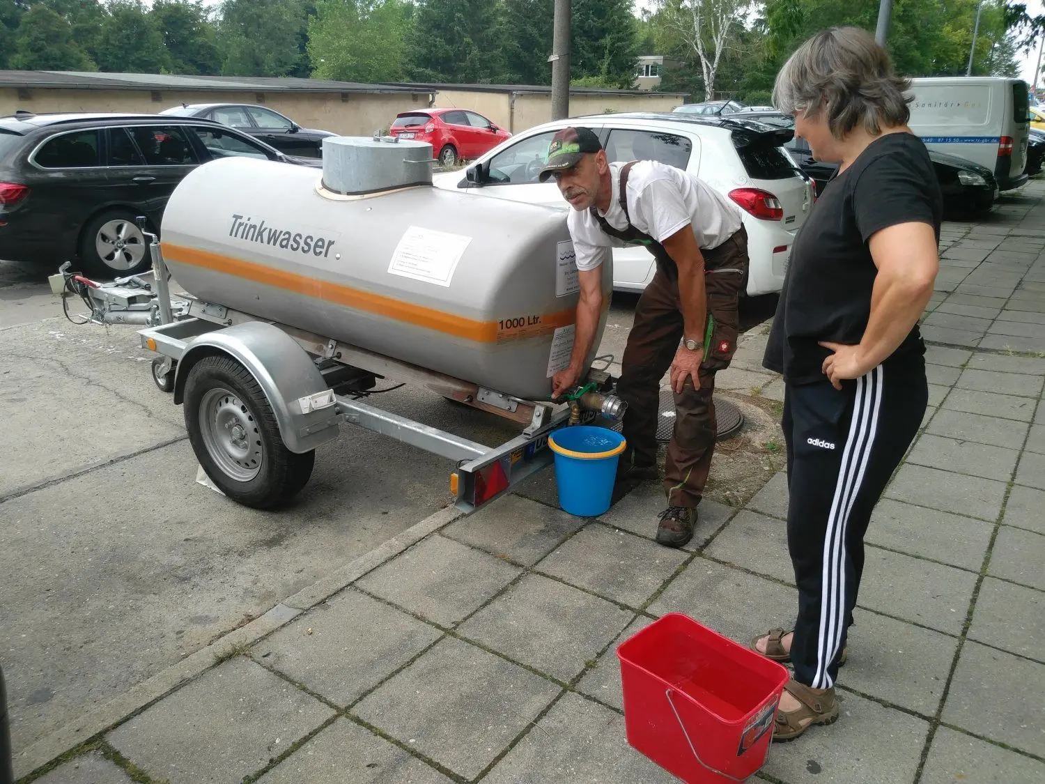 Am Tag danach: Rüdiger Klein holt sich mit einer weiteren Anwohnerin frisches Trinkwasser. Die Strom- und Wasserleitungen im Wohnblock der Rudolf-Breitscheid-Straße wurden nach dem Brand vorübergehend gekappt.