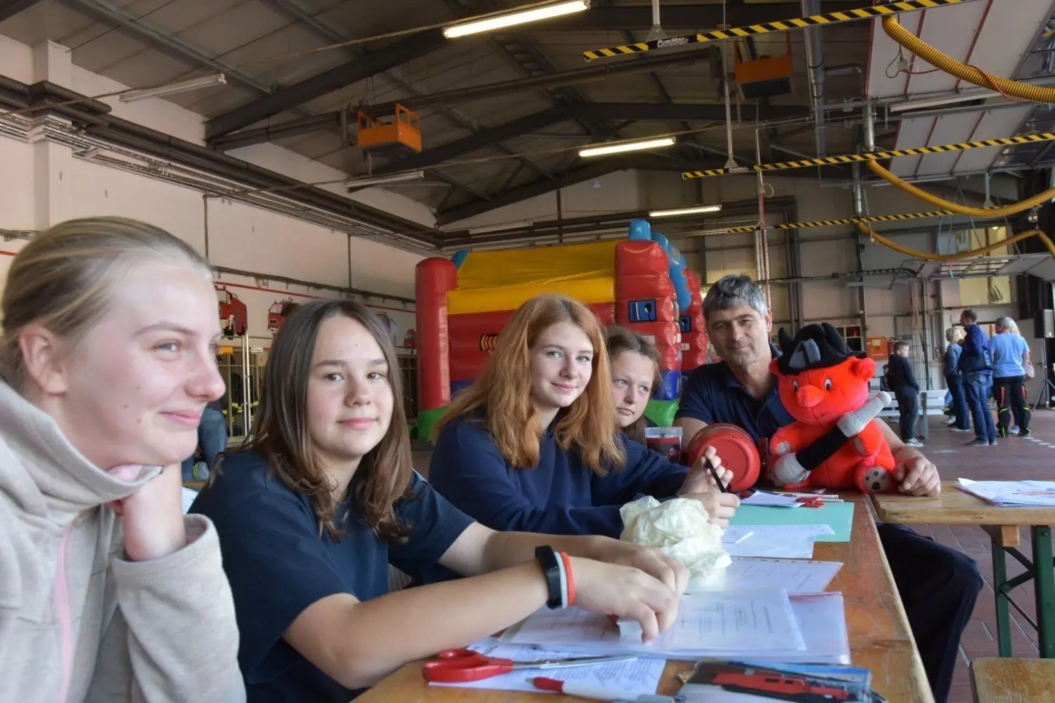 Der Nachwuchs hat Spaß bei der Feuerwehr, das ist den Mädchen Finja, Phoebe, Celine und Sophie (v.l.n.r.) deutlich anzusehen. Jugendausbildungsleiter Frank Hilbig (r.) hält derweil den namen- und beschäftigungslosen Feuerteufel im Arm.