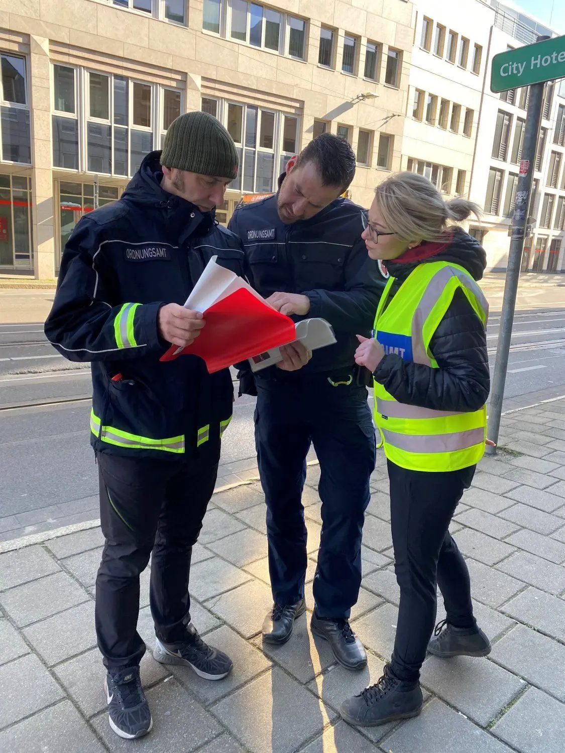 Ordnungsamt auf Streife: Peter Garlich, Tony Welzel und Michelle Marschall (v.l.) werfen selbst noch einmal einen Blick in die Verordnung über Maßnahmen zur Eindämmung des neuartigen Coronavirus SARS-CoV-2und COVID-19 in Brandenburg.