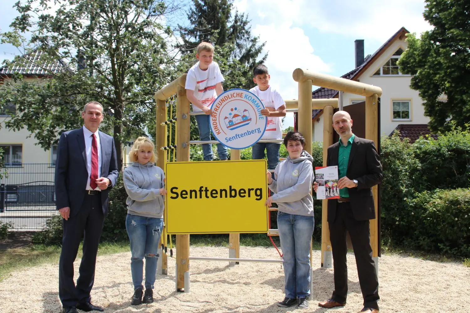 Die Stadt Senftenberg ist zum zweiten Mal mit dem Siegel "Kinderfreundliche Kommune" ausgezeichnet worden. Bürgermeister Andreas Fredrich (l.) sowie Malin Fromme und Tony Morath vom Kinder- und Jugendparlament nehmen das Siegel von Dominik Bär vom Verein K