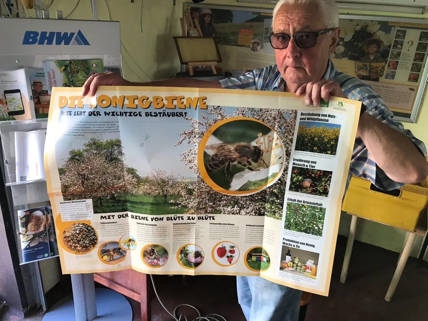 Hans-Jürgen Gräber zeigt ein Poster, auf dem Gäste Wissenswertes zu den Honigbienen erfahren können.