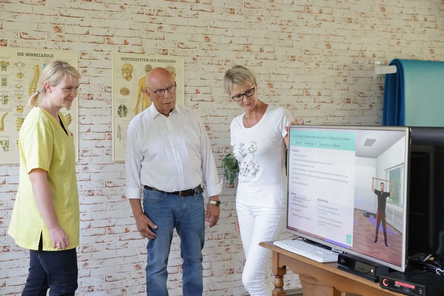 Im Therapiezentrum Cementa Feller (r.) in Senftenberg ist das internetbasierte Training vor einem großen Bildschirm möglich. Prof. Fritjof Reinhardt (M.) möchte erreichen, dass die App auch im häuslichen Umfeld anwendbar wird.