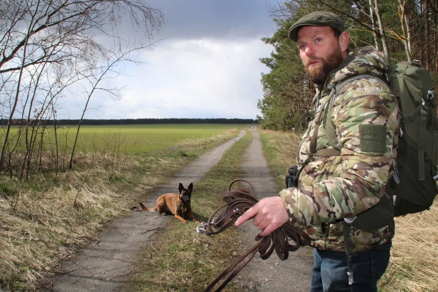 Naturführer Stephan Kaasche ist im Waldgebiet am Bergener See mit seiner Hündin Anima unterwegs. Die dreijährige Belgische Schäferhündin ist darauf trainiert, Wolfslosung aufzuspüren. Hier hat sie direkt am Waldweg ein „Häufchen“ gefunden und legt sich nieder.