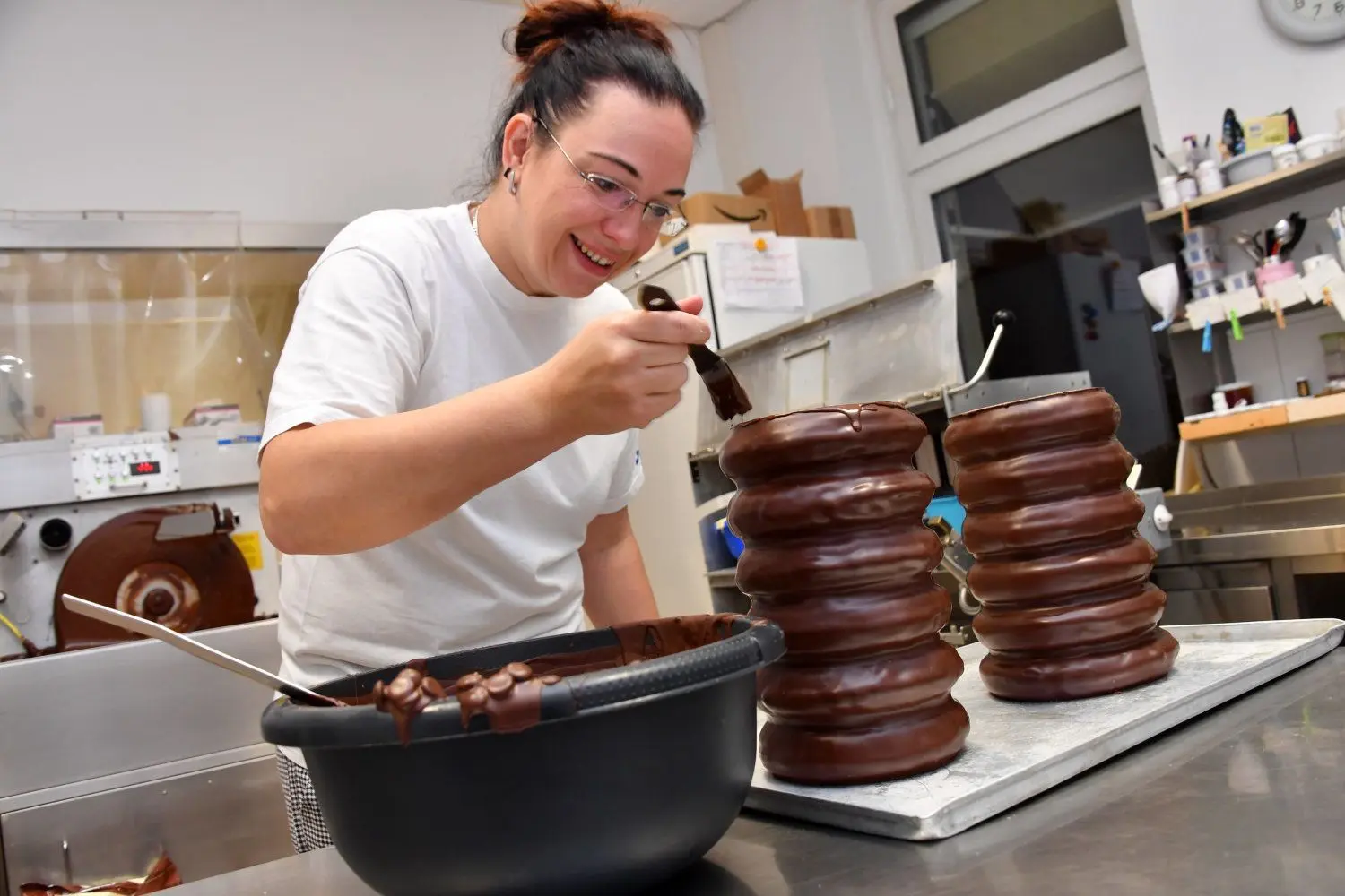 Konditorin Nicole Nitschke  „versiegelt“ die Schnittflächen der beiden großen konischen Baumkuchen  mit feinster Schokolade.