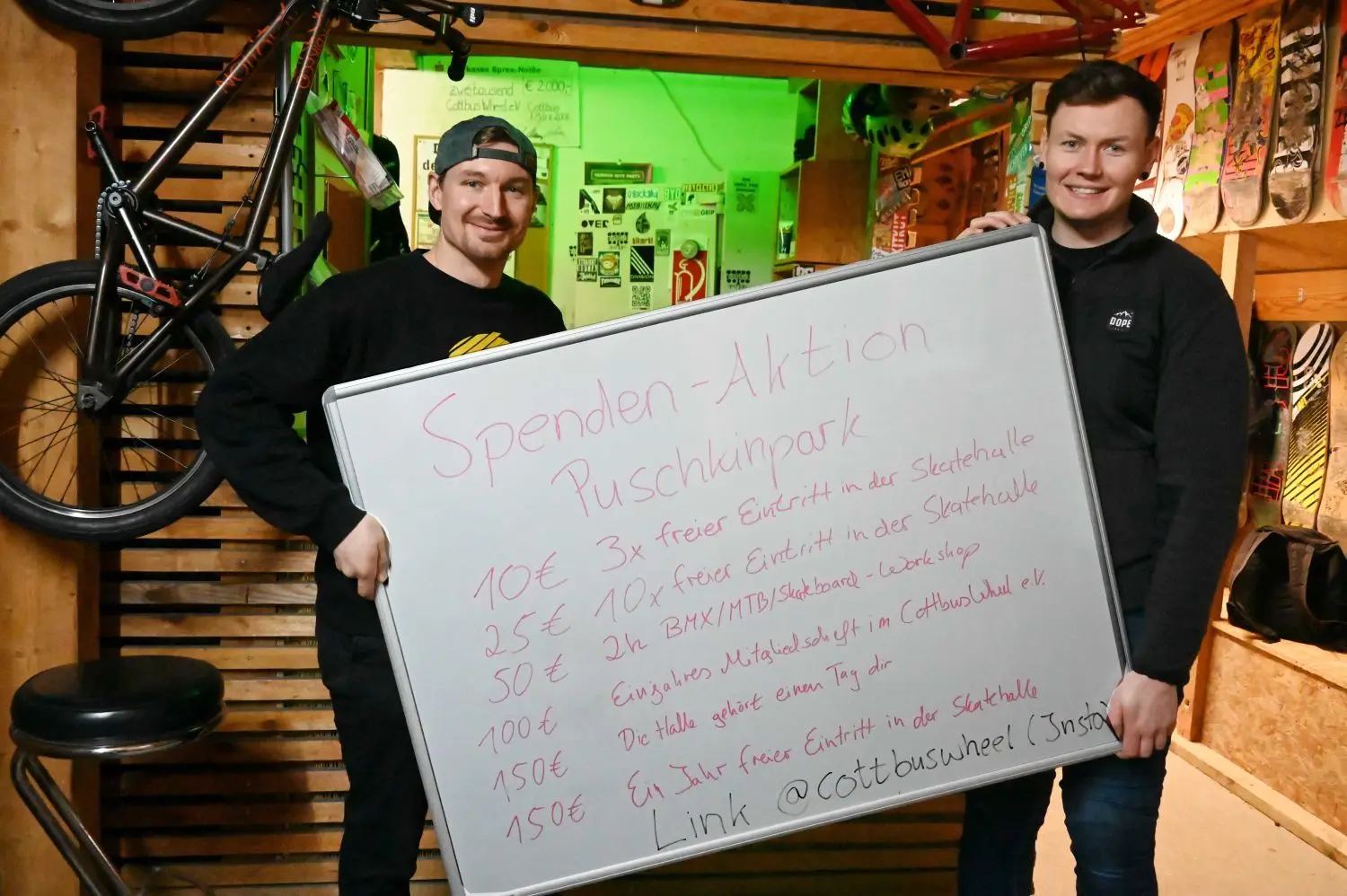 Der Verein Cottbus Wheel hat bei der Planung für den Skaterpark im Puschkinpark geholfen. Da das Fördergeld für die Erneuerung nicht reicht, hat der Verein ein Crowdfunding gestartet. Möglichst viele Menschen sollen mit kleinen Beträgen das Projekt unterstützen. David Henschel (l) und Paul Donath zeigen die Spendentafel.