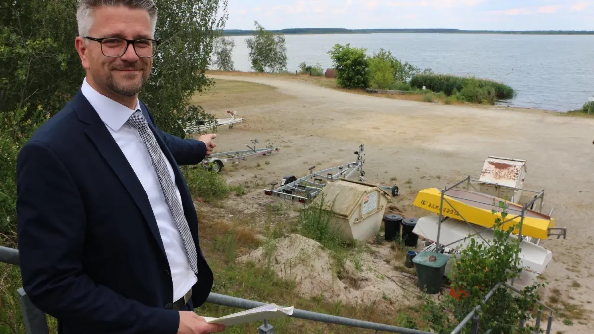Am Ufer vom Geierswalder See soll das Multifunktionsgebäude samt Wache der Wasserschutzpolizei im ersten Obergeschoss entstehen. Daniel Just, Geschäftsführer vom Zweckverband Lausitzer Seenland Sachsen, hat die Baupläne in der Hand.
Direkt am Ufer vom Geierswalder See soll das Multifunktionsgebäude samt Wache der Wasserschutzpolizei im ersten Obergeschoss entstehen. Daniel Just, Geschäftsführer vom Zweckverband Lausitzer Seenland Sachsen, hat die Baupläne in der Hand.