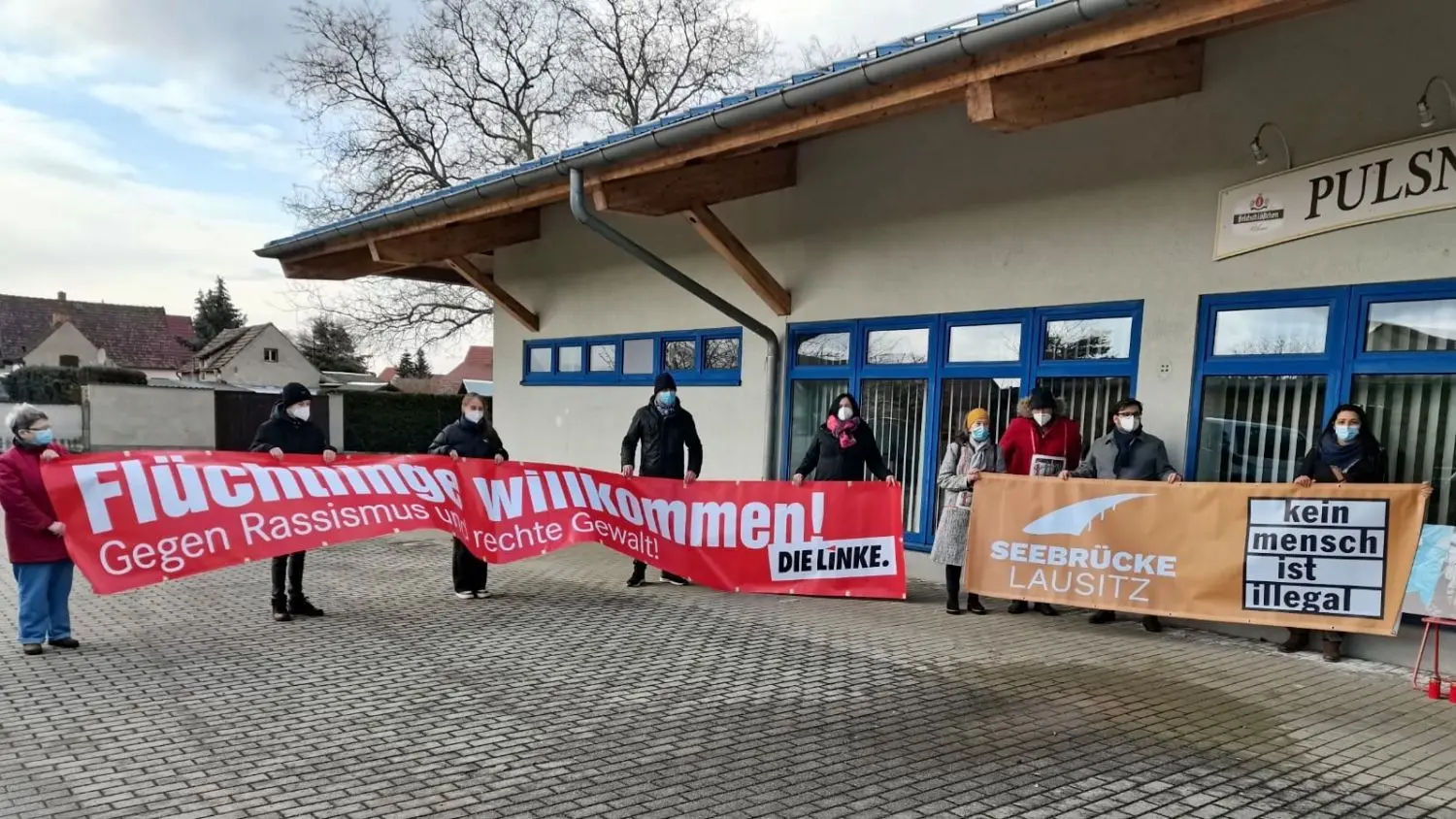 Mahnwache für Geflüchtete: Eine Stunde vorm Kreistag am 18. März in der Ortrander Pulsnitzhalle rollt die Intiative Seebrücke Lausitz die Banner für Flüchtlinge aus.