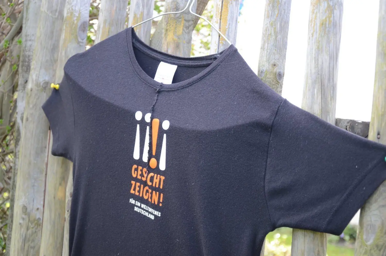 „Gesicht zeigen“ und „Für ein weltoffenes Deutschland“ steht auf dem T-Shirt, das Gertrud Riemer am Zaun ihrer Parzelle befestigt hat.