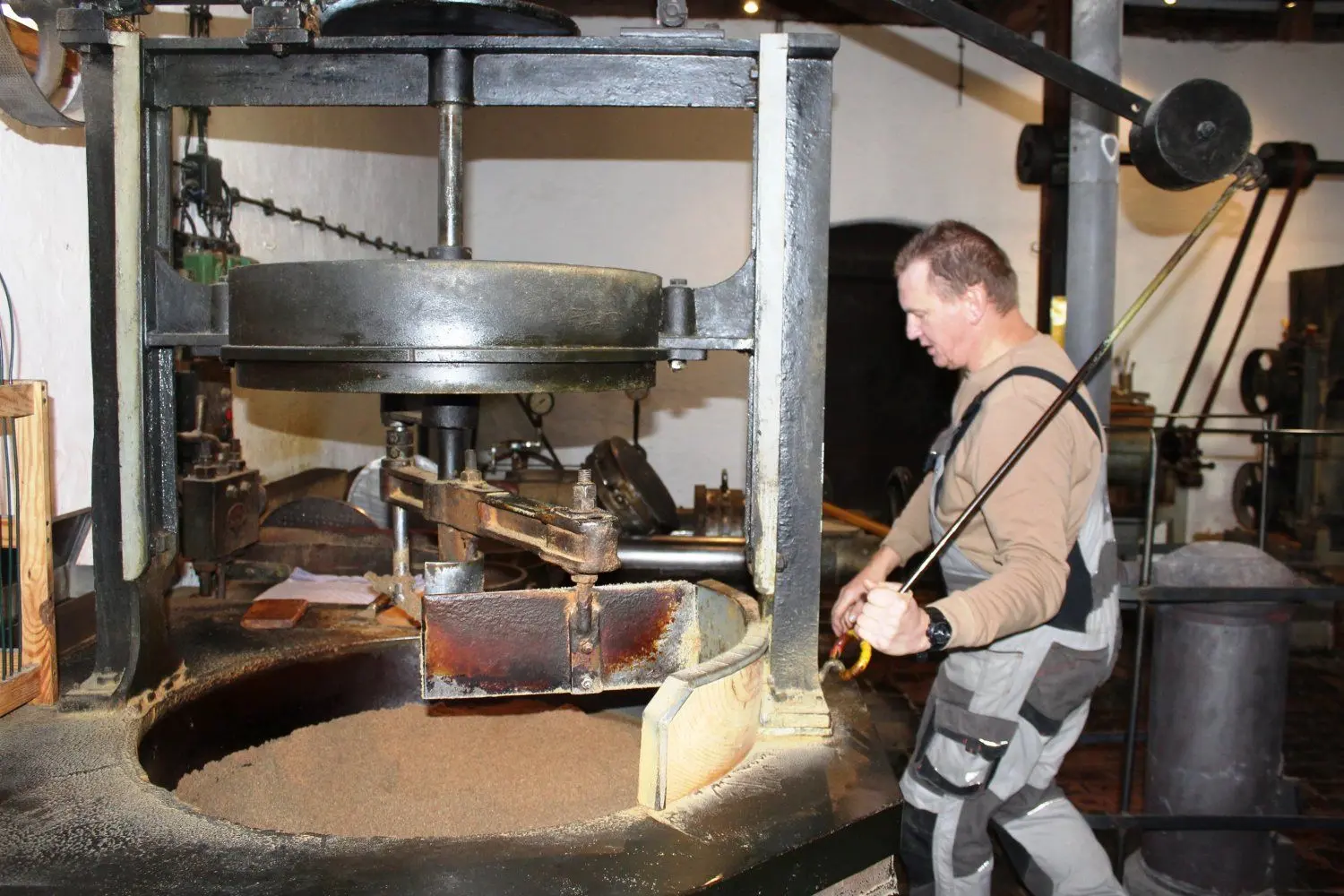 Torsten Schulz hebt das Rührwerk aus der Röstpfanne. Nach 30 Minuten ist die Masse getrocknet und kann gepresst werden.