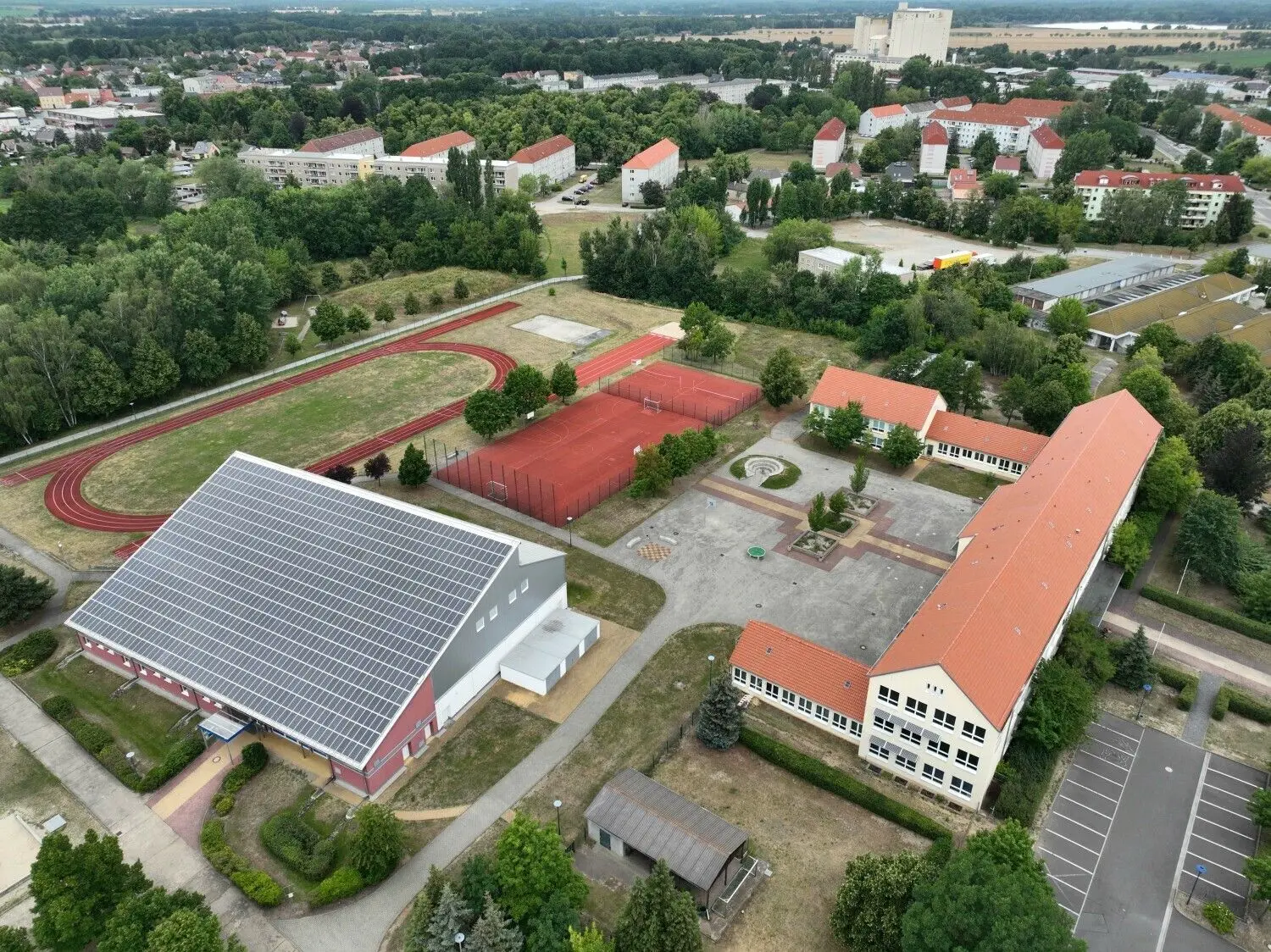 Luftaufnahme vom Sommer 2022 mit Blick auf das Schulzentrum „Dr. Albert Schweitzer” mit Grund- und Oberschule und angrenzendem Sportplatz. Das PVC-Dach wurde nun bei Vandalismus-Vorfällen beschädigt.