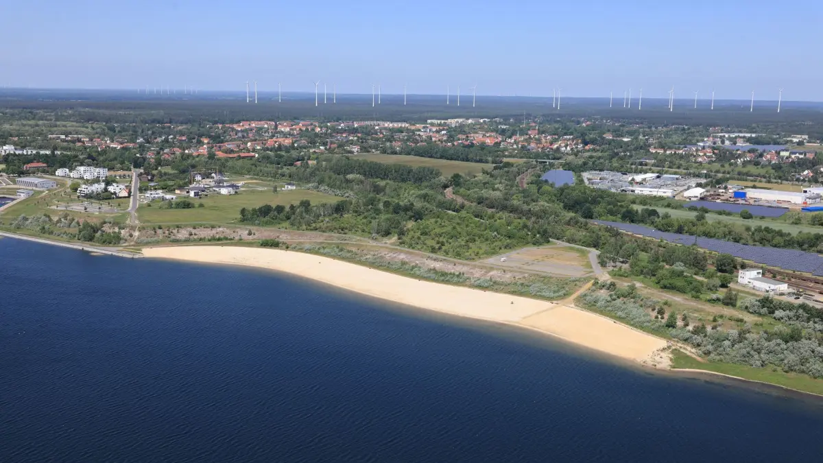 Blick von Süden auf den am Nordufer des Großräschener Sees gelegenen Stadtbadestrand. Die Straße links oberhalb des Strandes ist die Hafenstraße. An deren Ende soll in naher Zukunft ein Hotel oder ähnliches entstehen.