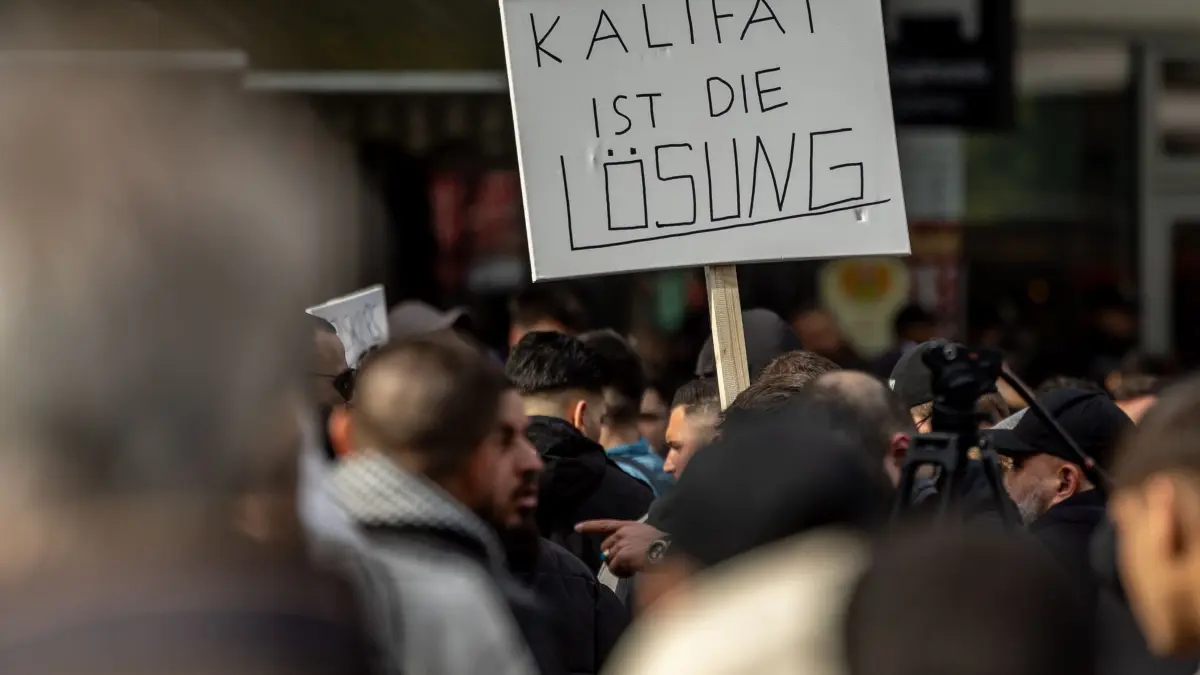 Demonstration der islamistischen Szene in Hamburg: ARCHIV - 27.04.2024, Hamburg: Teilnehmer einer Islamisten-Demo halten ein Plakat mit der Aufschrift „Kalifat ist die Lösung“ in die Höhe. (zu dpa: «Islamisten-Demos: Tschentscher stellt sich hinter Versammlungsbehörde») Foto: Axel Heimken/dpa +++ dpa-Bildfunk +++