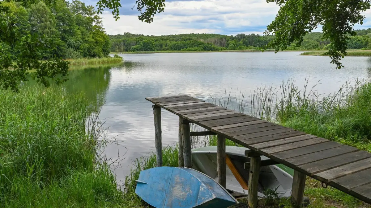Eine Szene, die es in Brandenburg mehrfach gibt: Im Osten, im Westen und im Süden trocknet mancher See aus — so wie der Pinnower See im Schlaubetal. Auch dort setzen sich Anwohner für dessen Erhalt ein. Doch über Lösungswege können die Meinungen weit auseinandergehen, das zeigt ein Fall in Oder–Spree.
Die Höhe eines Bootssteges verdeutlicht den enormen Wasserverlust im Pinnower Sees. Der See liegt im Naturpark Schlaubetal. Der Pegel des Sees sinkt seit Jahren immer weiter. Ursachen sind der Klimawandel und nach Anwohnern zufolge die Grundwasserabsenkungen durch den nahen Braunkohletagebau Jänschwalde. (zu «Ohne rasche Wassereinleitung droht Calpenzmoor das Aus») +++ dpa-Bildfunk +++
