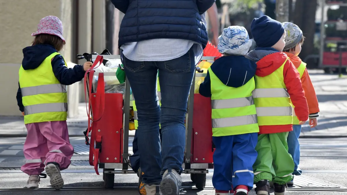 Kita–Kinder: ARCHIV - 17.04.2018, Bayern, München: ILLUSTRATION - Ein Betreuerin läuft mit mehreren Kleinkindern über einen Bürgersteig . (zu dpa: «Bessere Kinderbetreuung in Thüringen – Jobs in Kitas sicherer») Foto: Peter Kneffel/dpa +++ dpa-Bildfunk +++