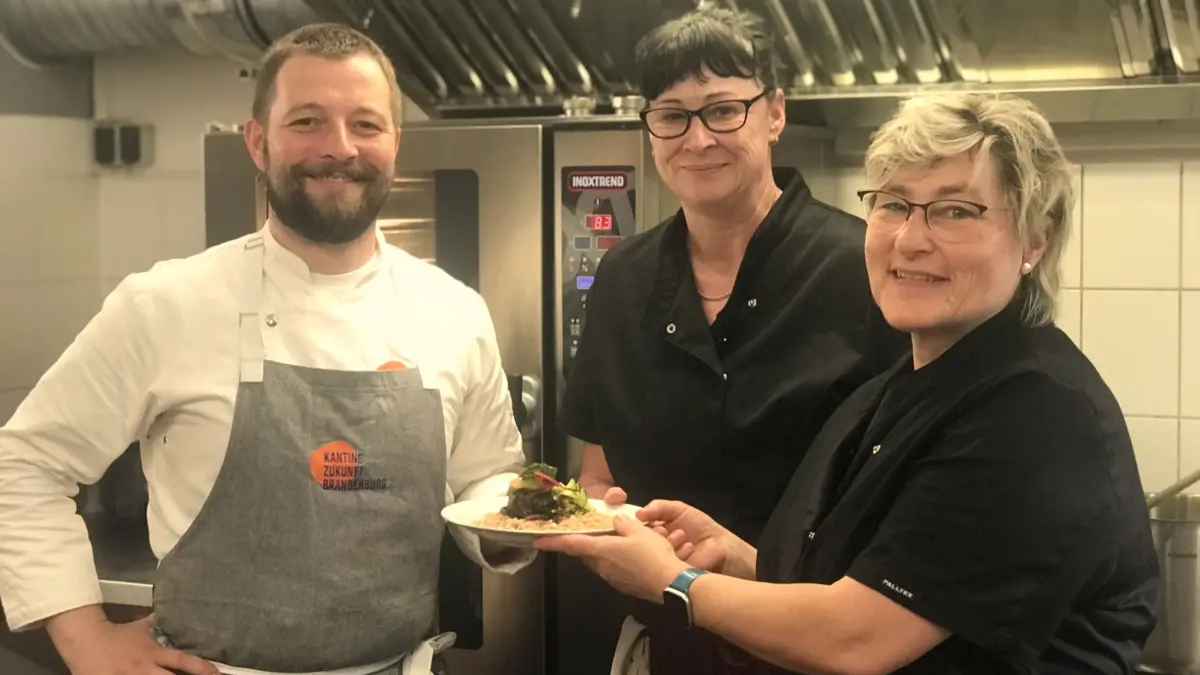 Karsten Schwarzenberg, Küchentrainer des Projekts Kantine Zukunft Brandenburg, zeigt den beiden Köchinnen der Schule in Eberswalde, Michaela Pogutke und Silvia Holzhausen, neue Rezepte.