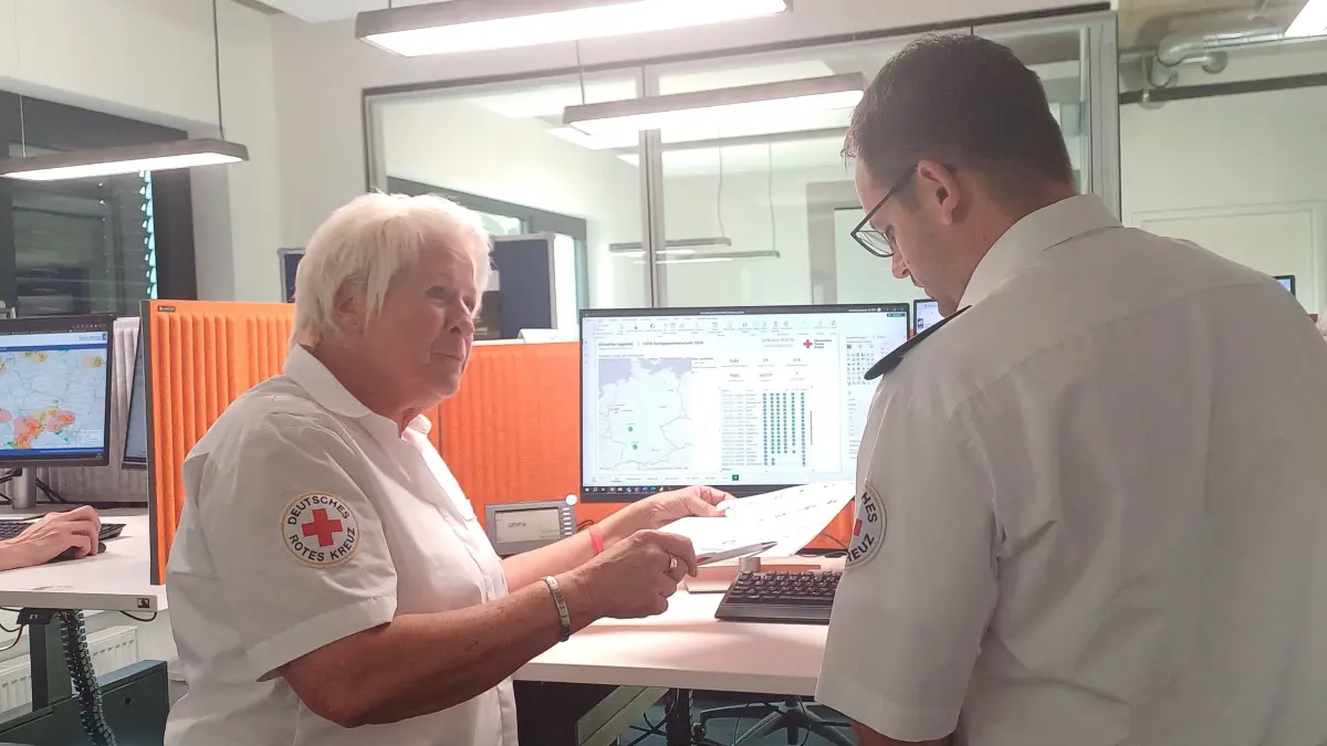 Regina Radloff (l.) aus Hessen bespricht im Lagezentrum des DRK in Berlin mit einem Kollegen die Einsätze rund um den 13. Spieltag der Fußball-EM.