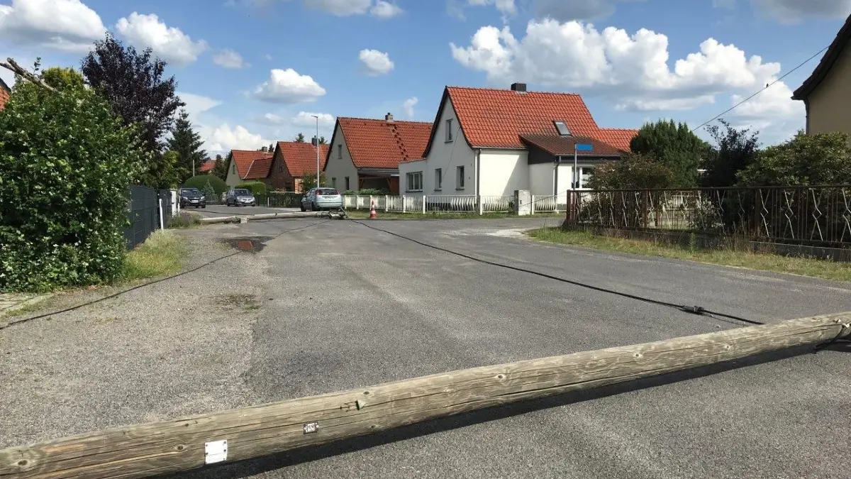 Ein umgeknickter Telefonmast liegt quer auf einer Straße in Ruhland.