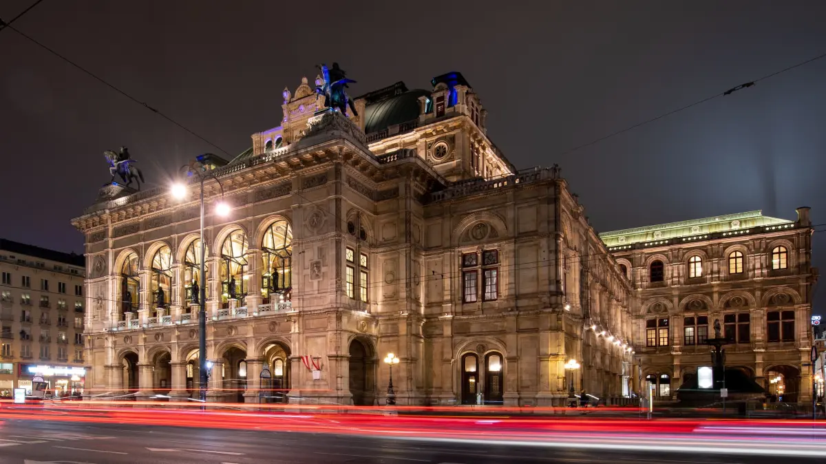 Die Lichter vorbeifahrender Autos sind vor der Wiener Staatsoper am Abend zu sehen. (zu dpa: "Wiener Staatsoper spielt nach Corona-Pause wieder auf") +++ dpa-Bildfunk +++