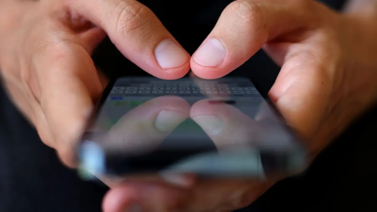 Warnung vor Phishing-SMS: ILLUSTRATION - 06.07.2022, Bayern, Augsburg: Person hält Handy in der Hand (zu dpa: «Festnahme - 20-Jähriger verschickt tausende Betrugs-SMS») Foto: Karl-Josef Hildenbrand/dpa +++ dpa-Bildfunk +++