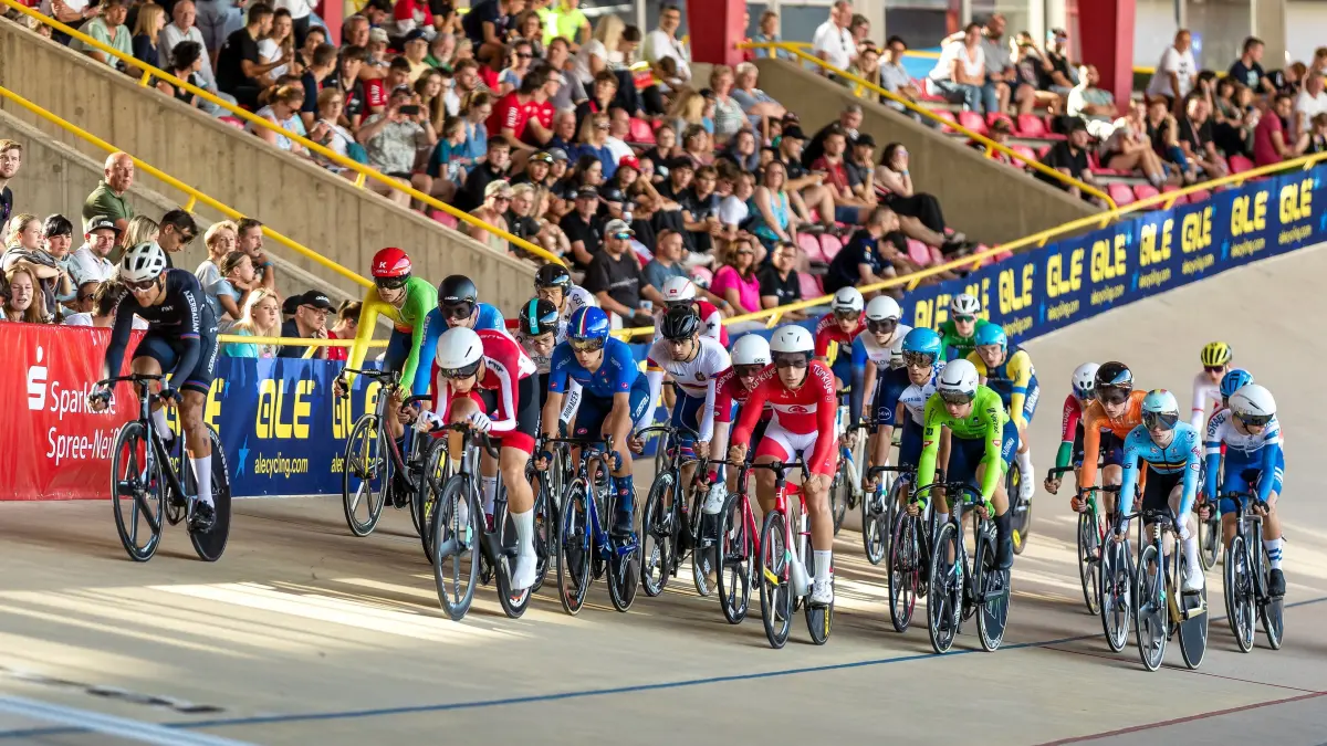 Bahnrad EM U19 / U23: Bahnrad Europameisterschaft der Altersklassen Junioren und U23 - Entscheidung im Punktefahren der Junioren: Zahlreiche Zuschauer sitzen auf der Tribüne, während die Sportler auf der Bahn um Punkte fahren.