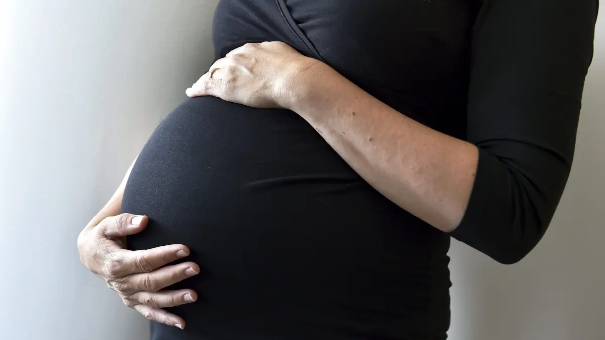 Eine schwangere Frau hält sich den Bauch. +++ dpa-Bildfunk +++
