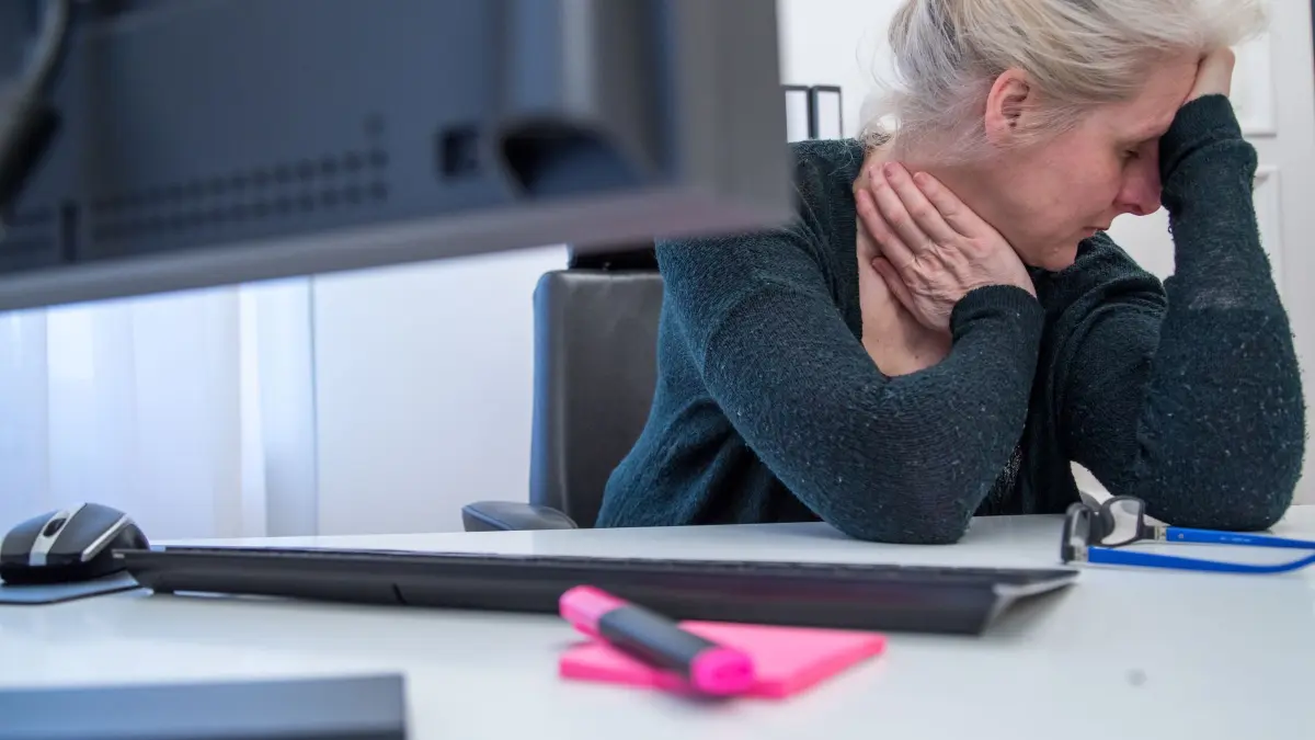 Eine Frau stützt ihren Kopf auf die Hand am Arbeitsplatz: ILLUSTRATION - Jobfrust und keine Veränderung in Sicht: Viele Menschen trauen sich nicht, den Arbeitsplatz zu wechseln. (zu dpa: «Raus aus dem alten Job? So schaffen Sie den Absprung») Foto: Christin Klose/dpa-tmn - Honorarfrei nur für Bezieher des dpa-Themendienstes +++ dpa-Themendienst +++