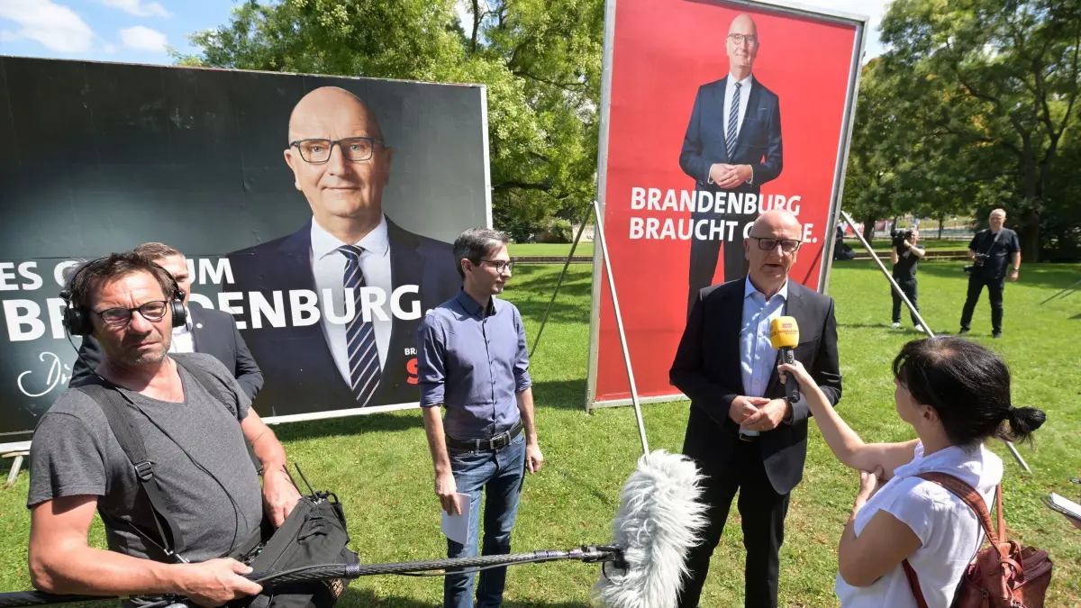 SPD-Plakatkampagne zur Landtagswahl in Brandenburg: 01.08.2024, Brandenburg, Potsdam: Brandenburgs Ministerpräsident und Spitzenkandidat, Dietmar Woidke (2.v.r., SPD), spricht zusammen mit dem SPD-Generalsekretär in Brandenburg, David Kolesnyk, auf dem Potsdamer «Platz der Einheit» zu Journalisten. Woidke stellt die Plakatkampagne der SPD zur Landtagswahl in Brandenburg vor. Foto: Michael Bahlo/dpa +++ dpa-Bildfunk +++