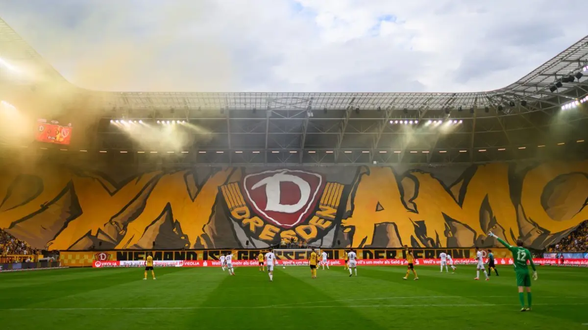 SG Dynamo Dresden -FC Energie Cottbus: 09.08.2024, Sachsen, Dresden: Fußball: 3. Liga, SG Dynamo Dresden - FC Energie Cottbus, 2. Spieltag, Rudolf-Harbig-Stadion. Dynamos Fans im K-Block zeigen eine Blockfahne und zünden Pyrotechnik. Foto: Robert Michael/dpa/ZB - Honorarfrei nur für Bezieher des Dienstes ZB-Funkregio Ost +++ ZB-FUNKREGIO OST +++