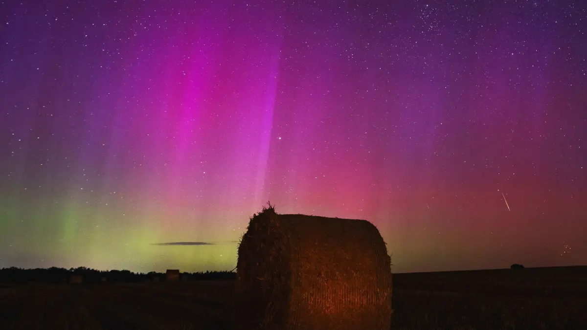 Polarlichter am Brandenburger Himmel: 13.08.2024, Brandenburg, Betzin: Polarlichter (Aurora borealis), genauer Nordlichter, scheinen am Himmel, während eine Sternschnuppe über einem Strohballen am Himmel verglüht. Der Sternschnuppenstrom der Perseiden entfaltet in diesen Nächten seine maximale Pracht mit einem Maximum von bis zu 100 Sternschnuppen pro Stunde. Wie jedes Jahr im August kreuzt die Erde Trümmerteilchen eines Kometen, genannt Perseiden. (zu dpa: «Polarlichter und Sternschnuppen am Nachthimmel») Foto: Georg Moritz/dpa +++ dpa-Bildfunk +++