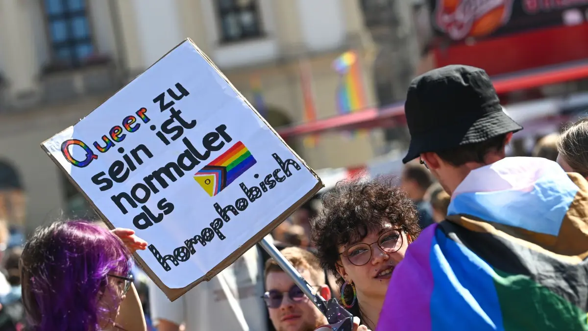 Christopher Street Day - Magdeburg: 24.08.2024, Sachsen-Anhalt, Magdeburg: Teilnehmer halten beim Christopher Street Day (CSD) in der Innenstadt ein Plakat mit der Aufschrift "Queer zu sein ist normaler als homophobisch". Für Vielfalt und Toleranz gehen Tausende Menschen auf die Straße. Foto: Heiko Rebsch/dpa +++ dpa-Bildfunk +++