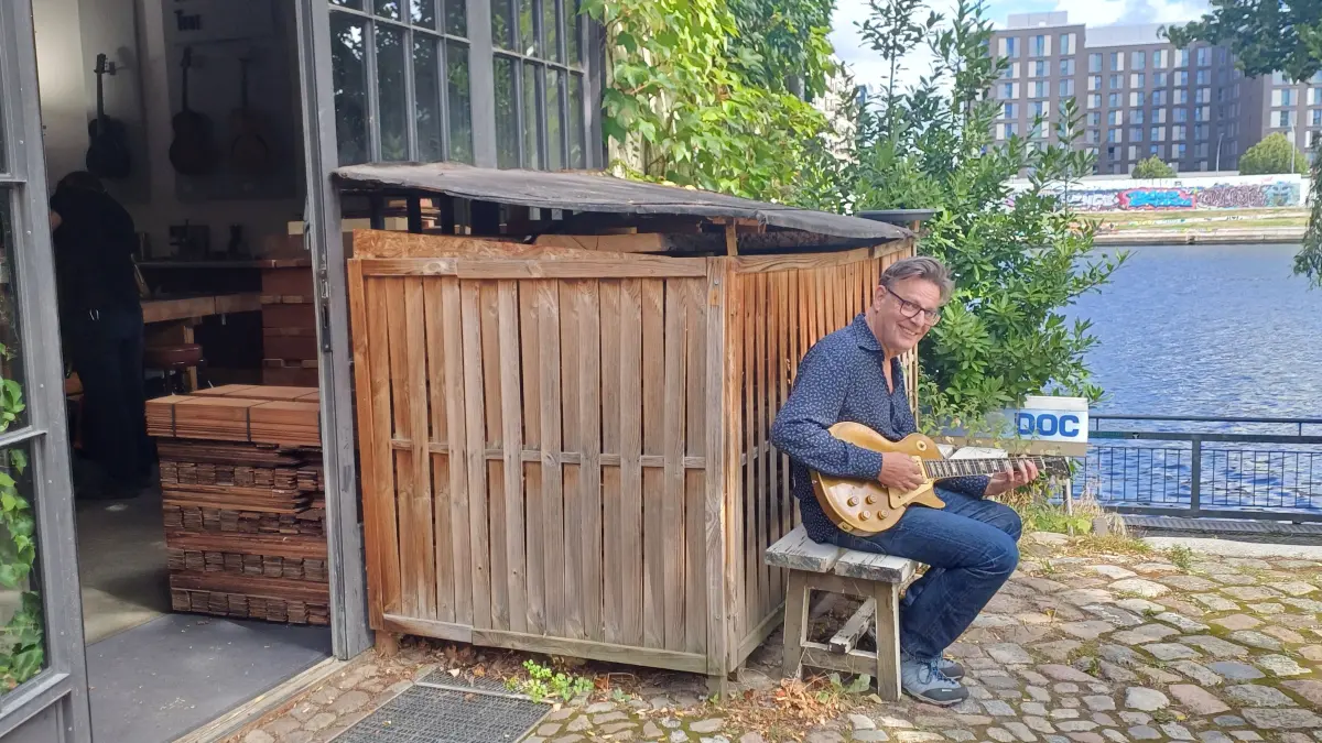 Lutz Heidlindemann mit eigener Vintage-Gitarre vor seiner Werkstadt am Spreeufer in Berlin-Kreuzberg